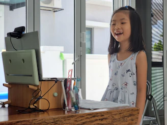 a little girl standing in front of a computer