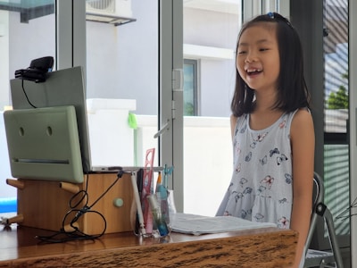 a little girl standing in front of a computer
