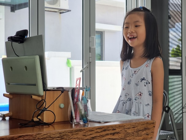 a little girl standing in front of a computer