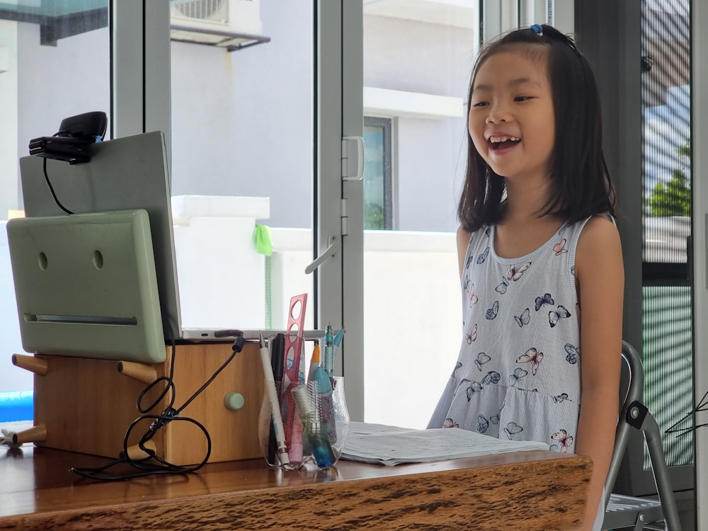 a little girl standing in front of a computer