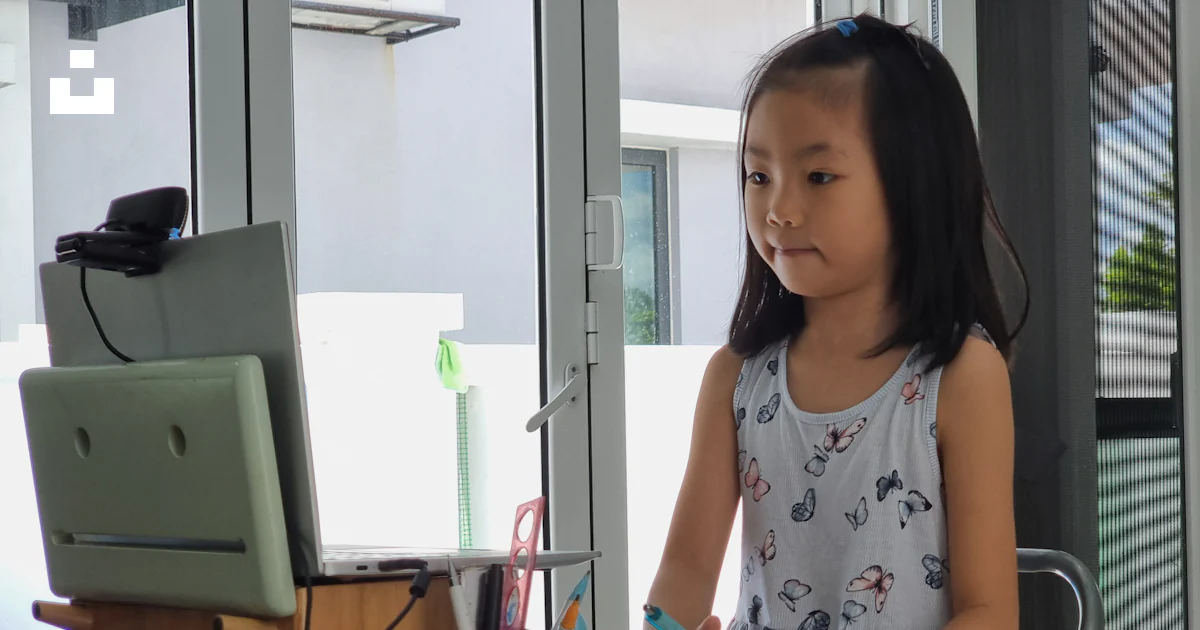 A little girl standing in front of a computer photo – Free Kids ...