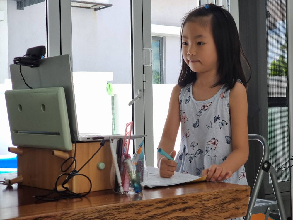 a little girl standing in front of a computer