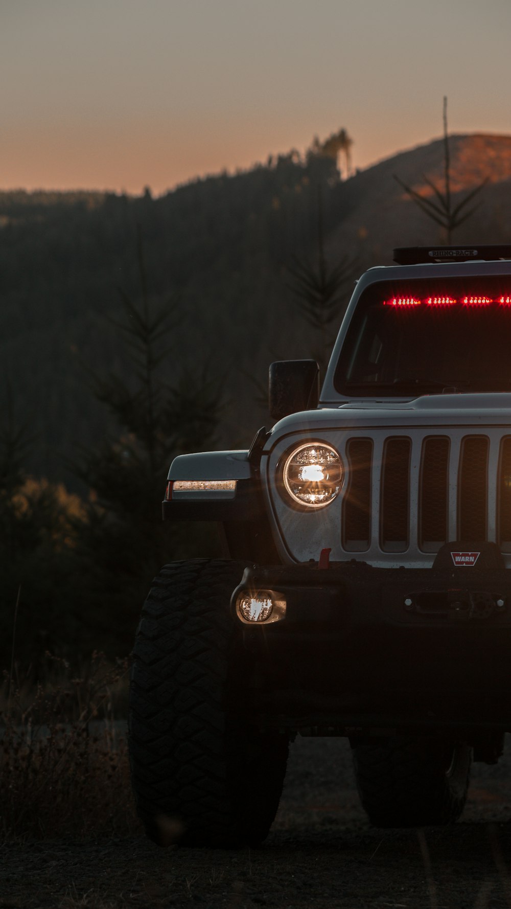 a jeep with its lights on is parked in a field