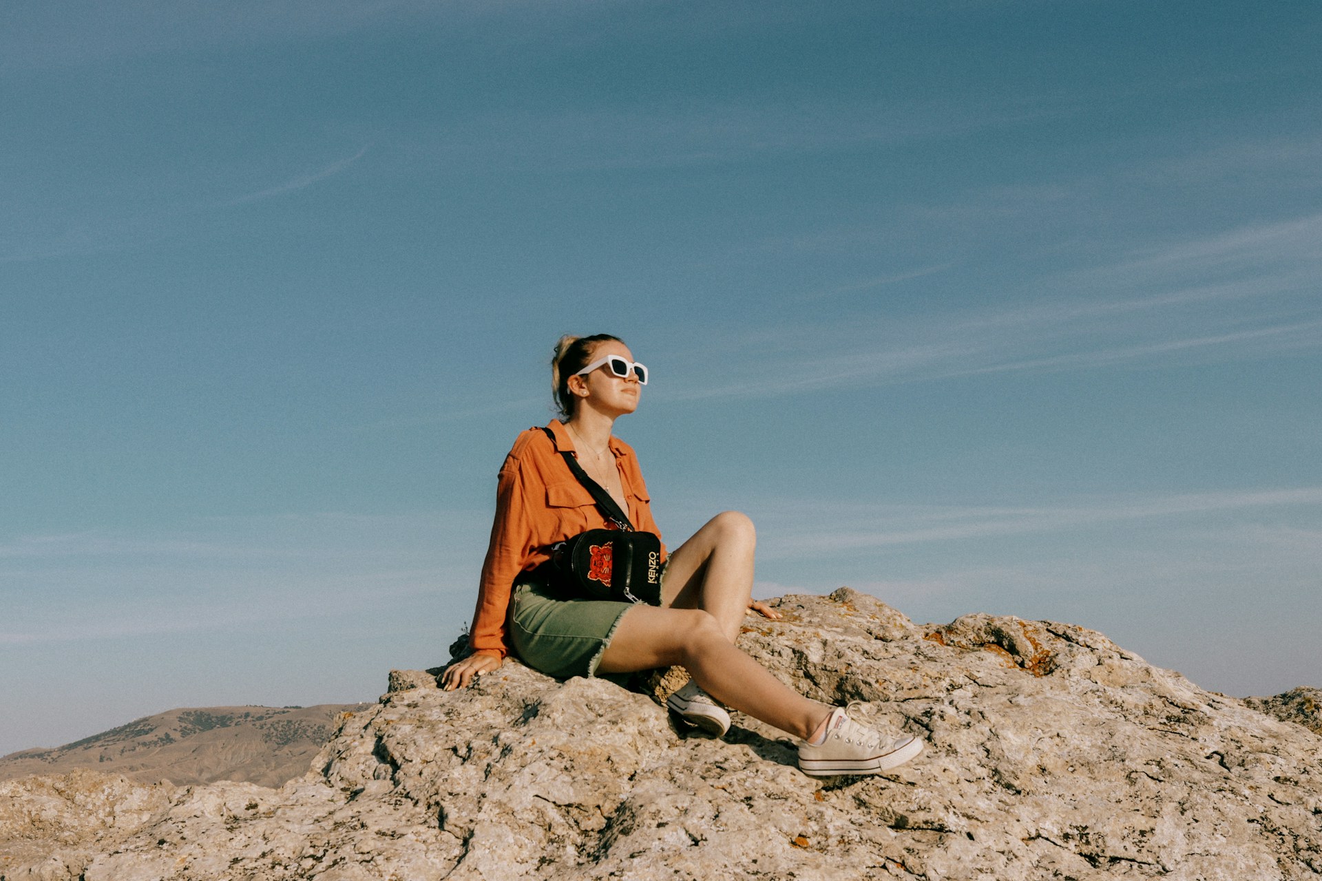 a woman sitting on top of a large rock