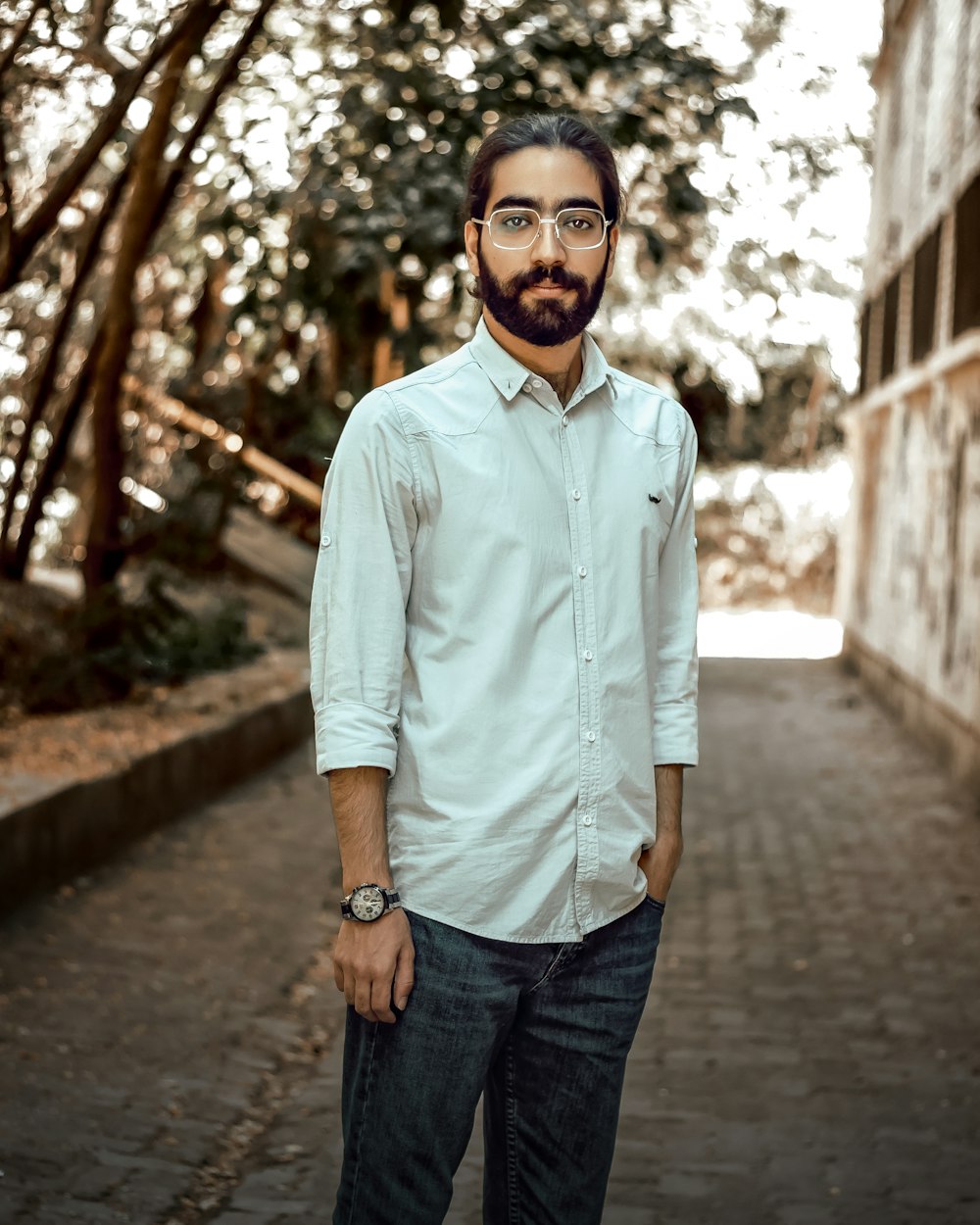 a man with a beard and glasses standing on a brick road