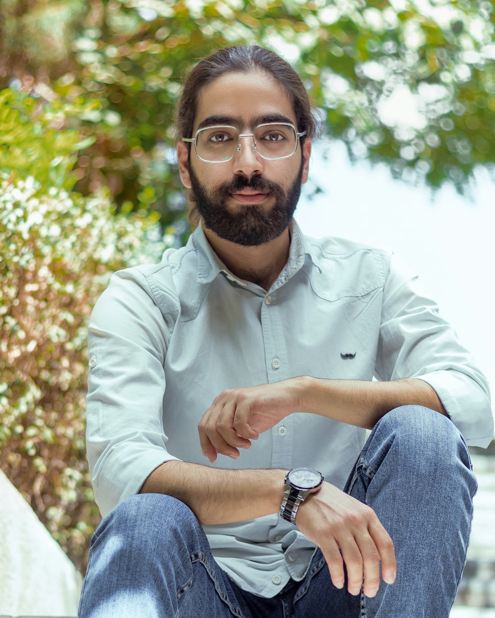 a man with a beard and glasses sitting on a bench