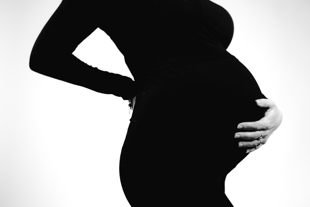 a pregnant woman poses for a black and white photo