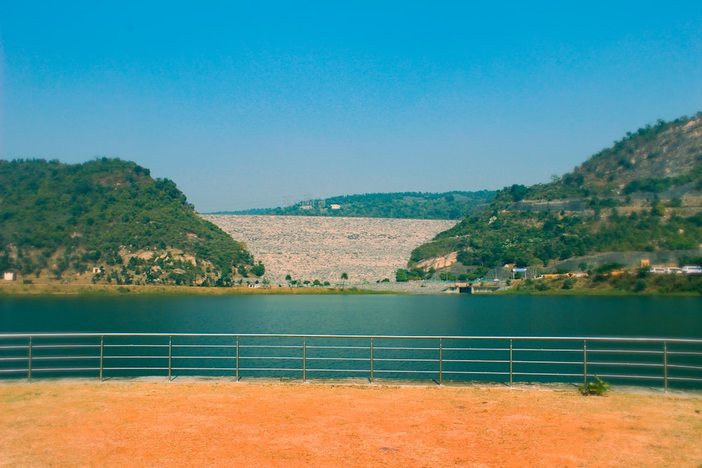 a large body of water sitting next to a lush green hillside