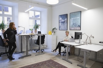 a woman standing in front of a desk with a laptop computer