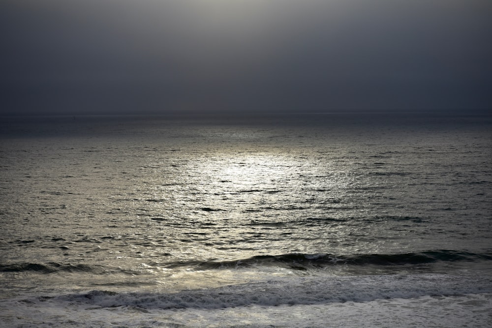 the sun is shining over the ocean on a cloudy day