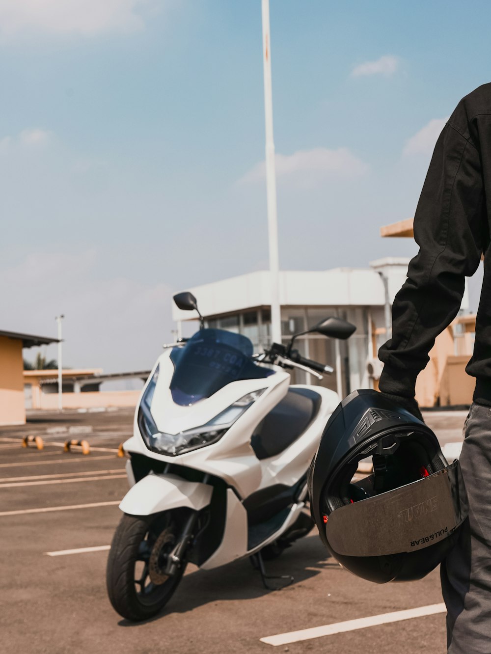 a man standing next to a motorcycle in a parking lot