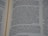 A close-up view of an open book page displaying text in English. The layout appears to be similar to that of a religious or classical text, possibly a Bible, as indicated by the column format and verse numbers. The text discusses a message regarding a skilled individual named Huram-Abi and refers to craftsmanship in various materials.