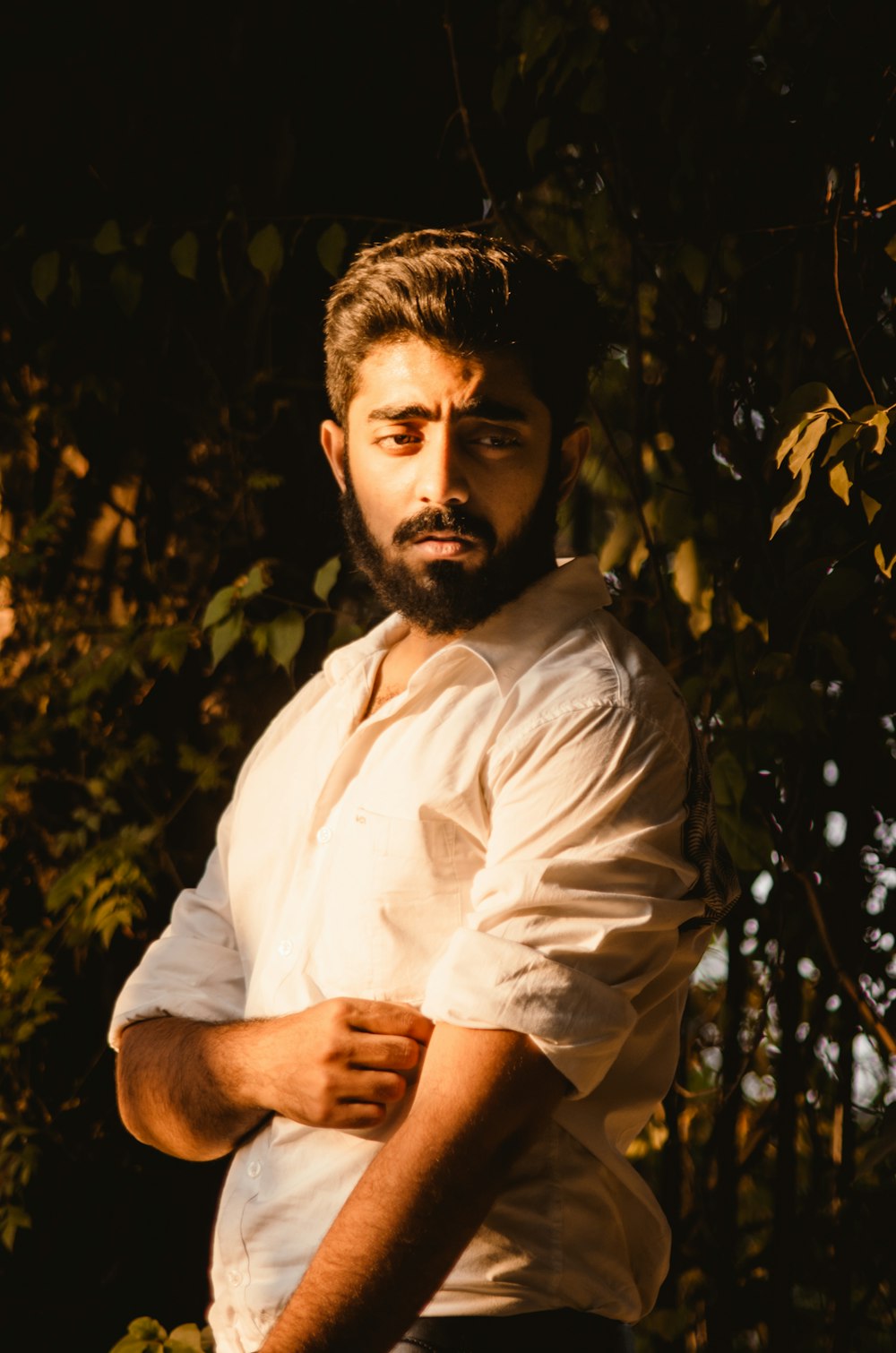 a man with a beard standing in front of a tree