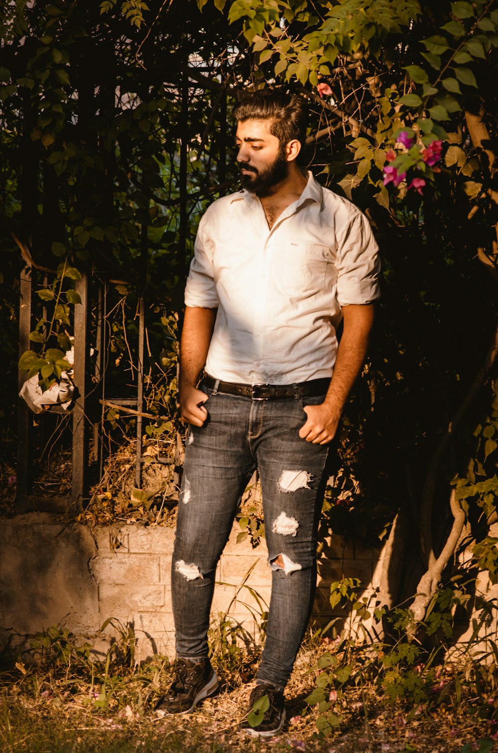 a man standing in front of a tree with his hands in his pockets