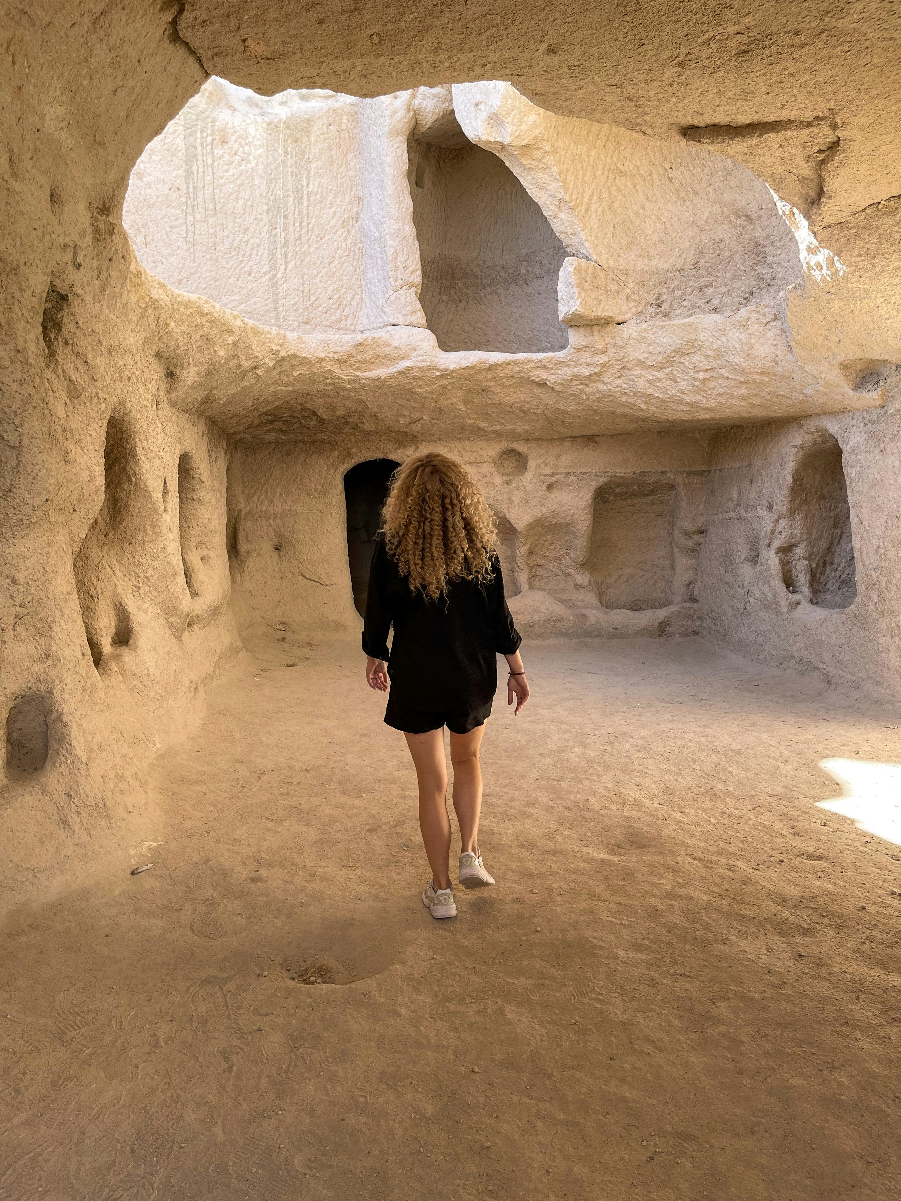 a woman is walking through a cave like area