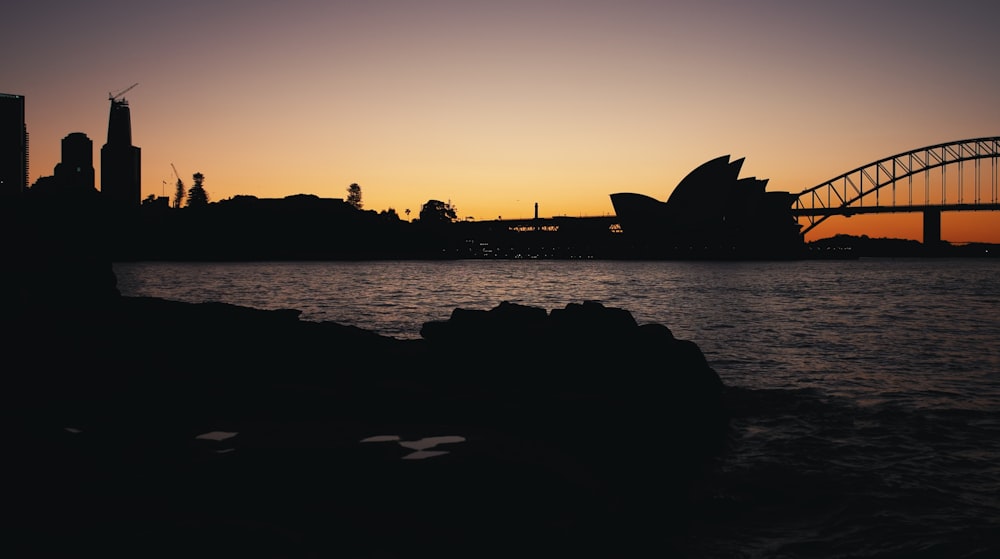 a sunset view of the sydney opera house and the sydney bridge