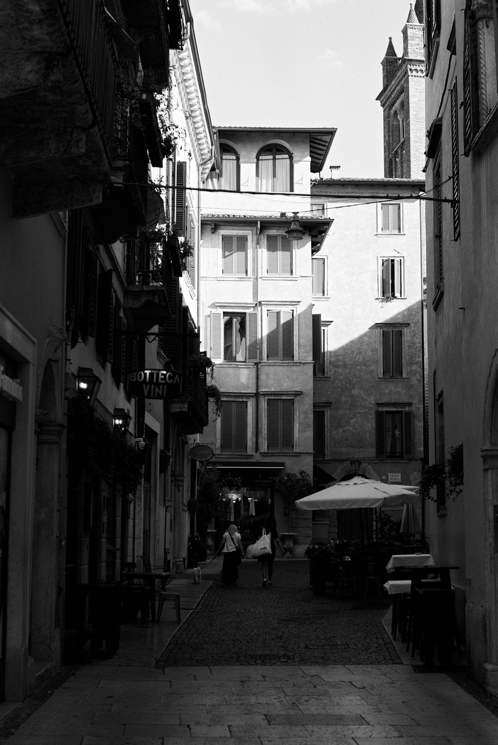 a black and white photo of people walking down a street