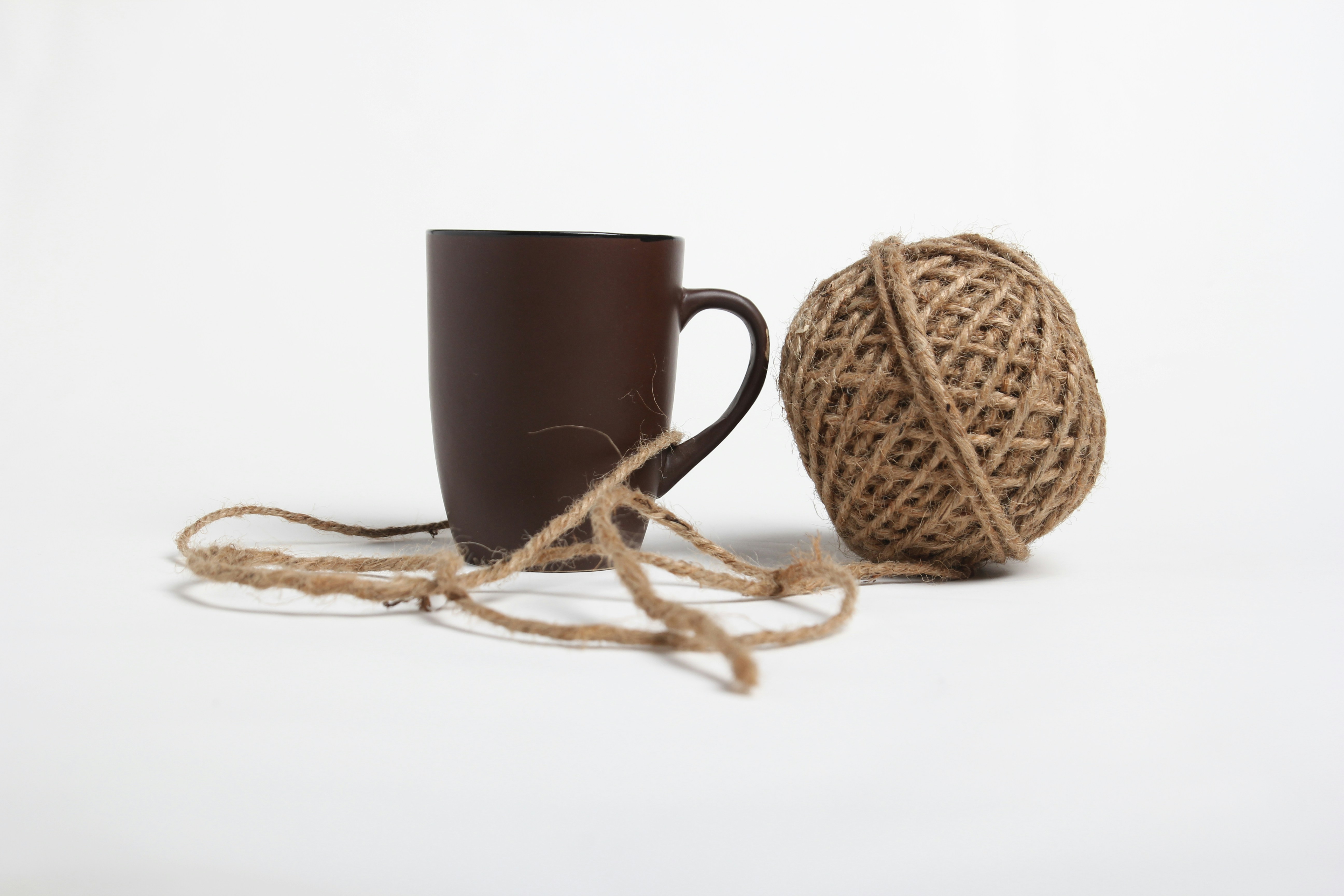 a ball of twine next to a coffee cup