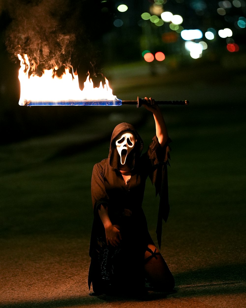 Eine Person in einer Maske, die einen Stock mit einem Feuer im Hintergrund hält