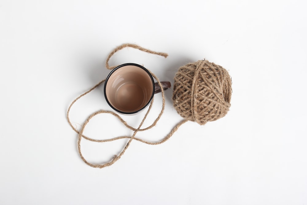 a ball of twine next to a coffee cup