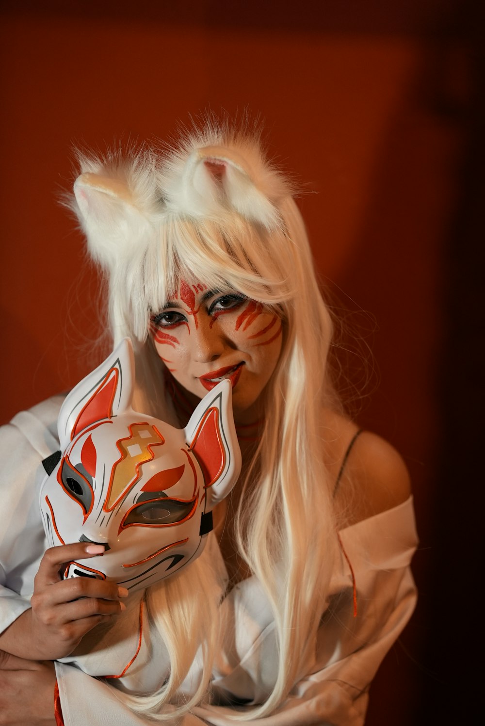 a woman with white hair and makeup holding a mask