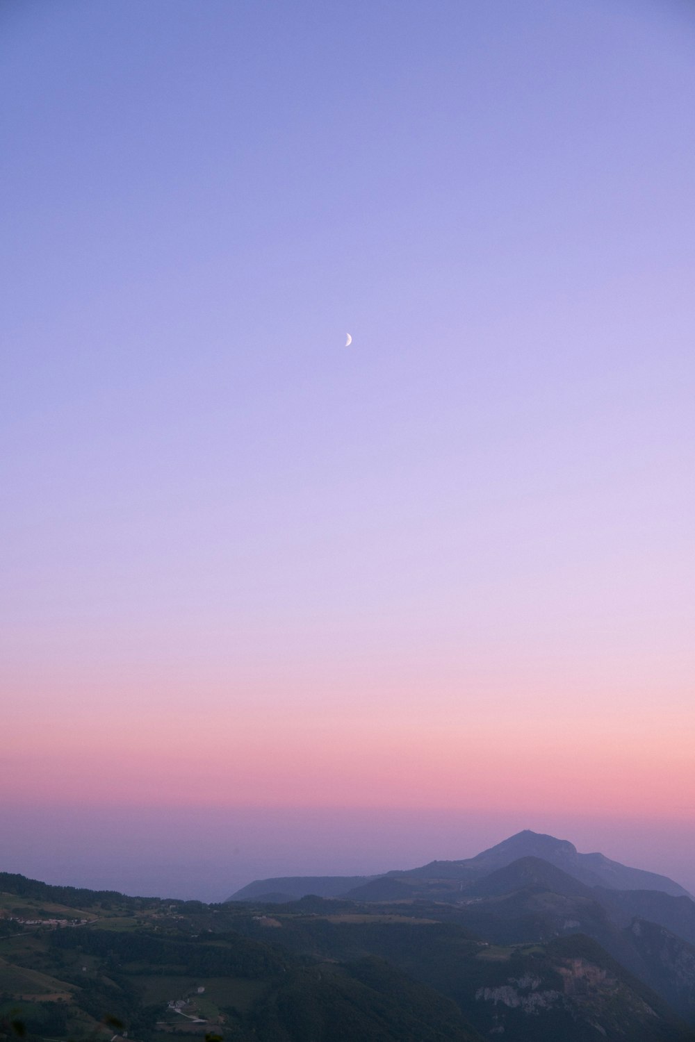 a view of a hill with a moon in the sky