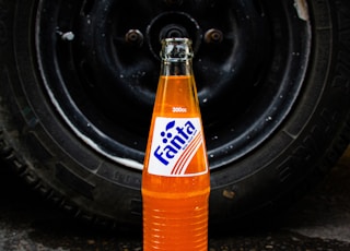 a bottle of soda sitting on the ground next to a tire
