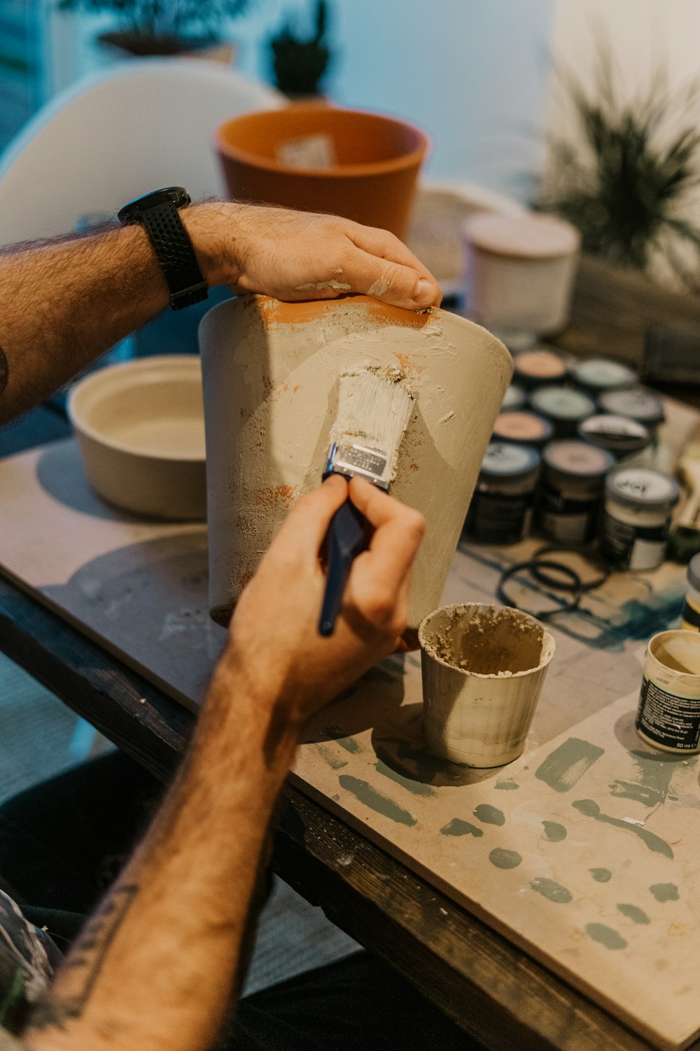 a man is painting a vase on a table