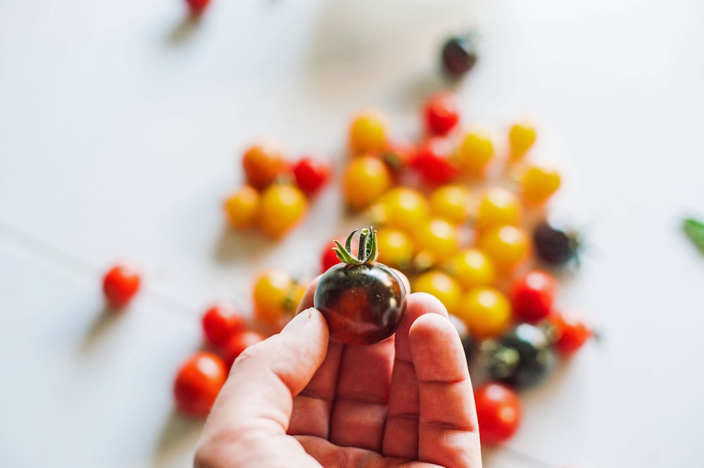 a person holding a tiny cherry in their hand