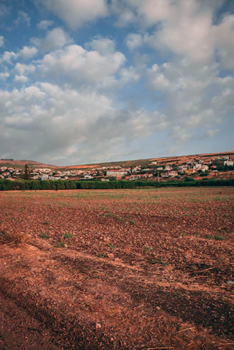 a dirt field with houses in the distance