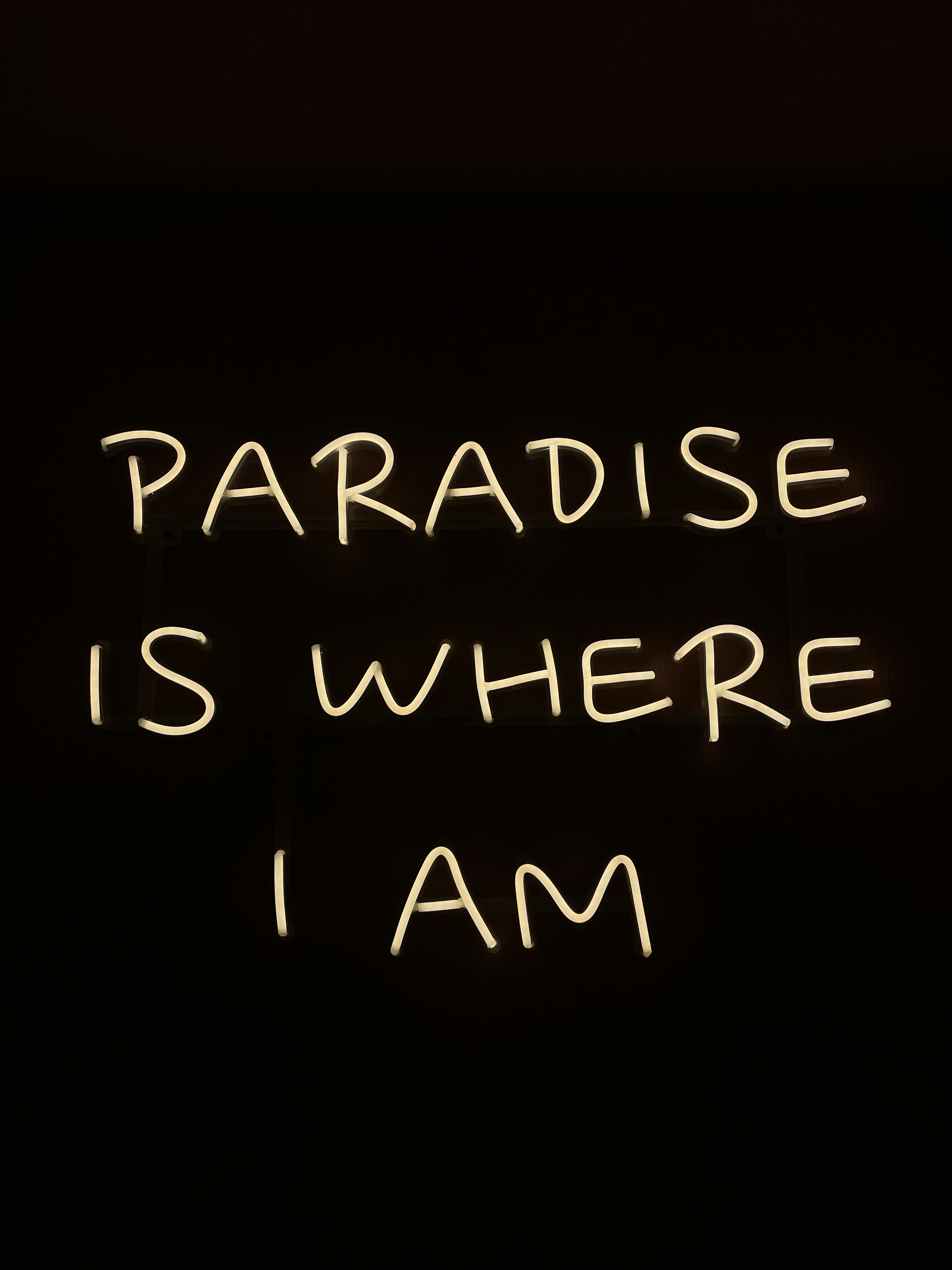 a neon sign that says paradise is where i am