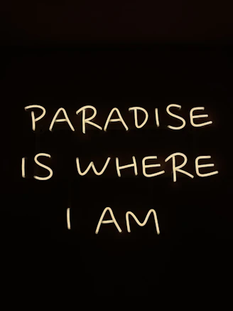 a neon sign that says paradise is where i am