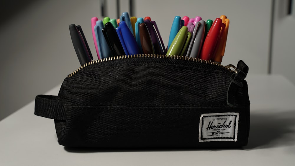 a black pencil holder filled with pens and markers