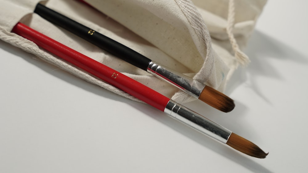 two red and black brushes in a white bag