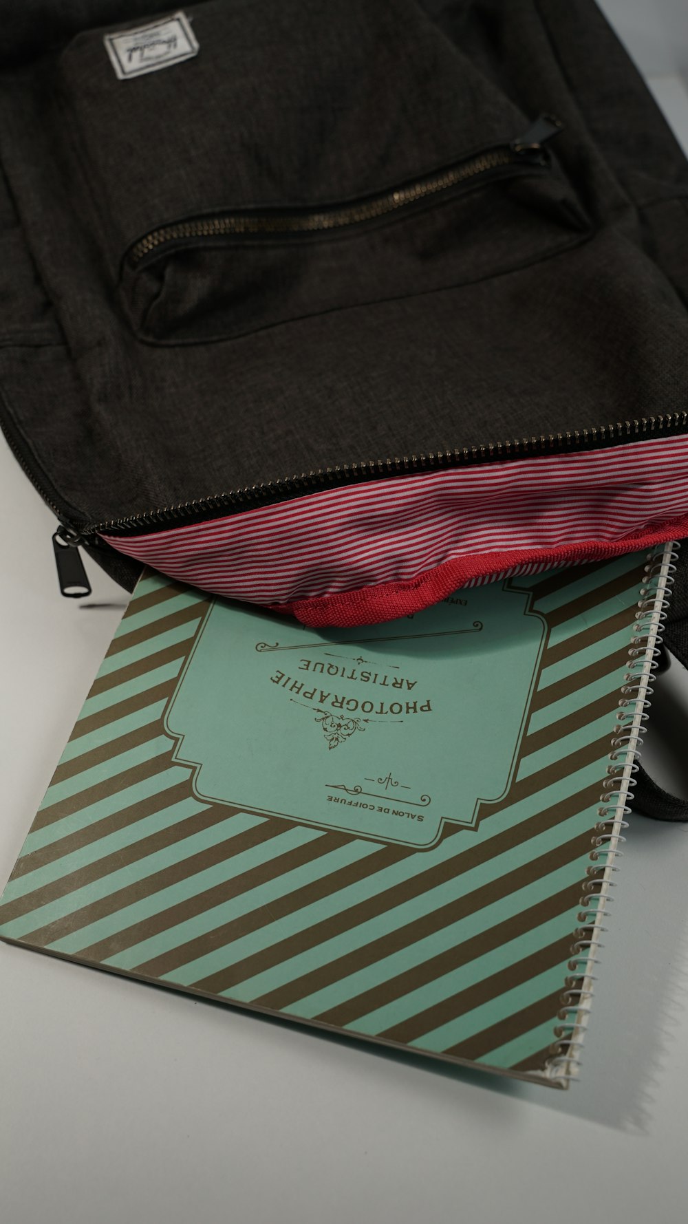 a black bag with a red stripe and a notebook on top of it