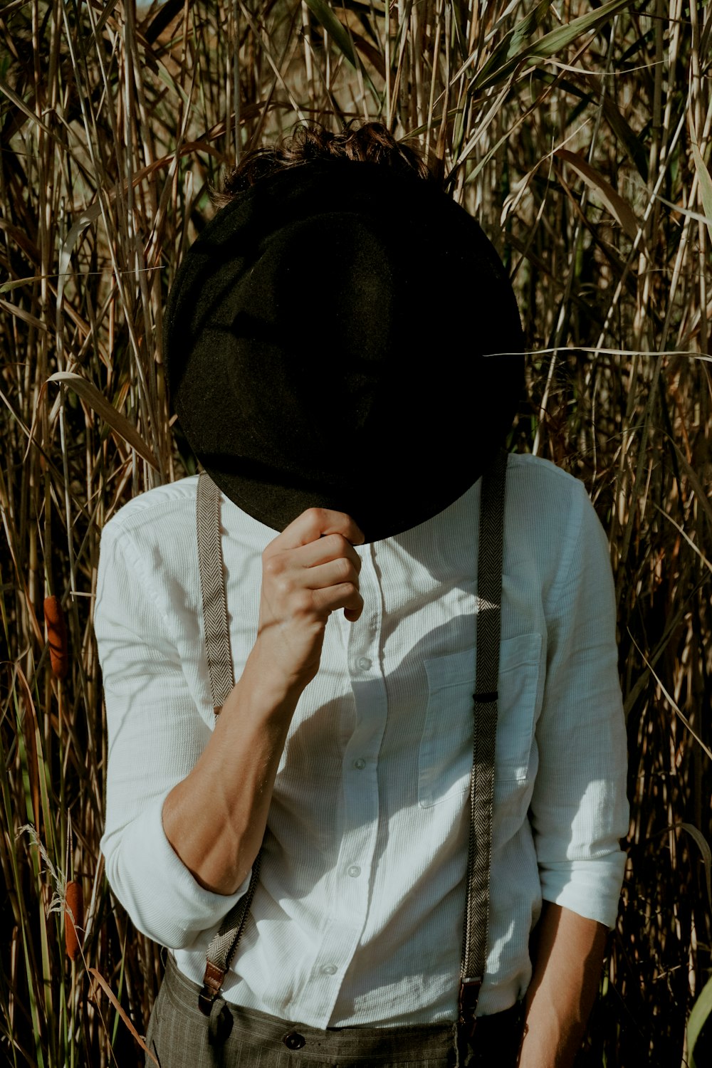 a person wearing a hat and suspenders in a field