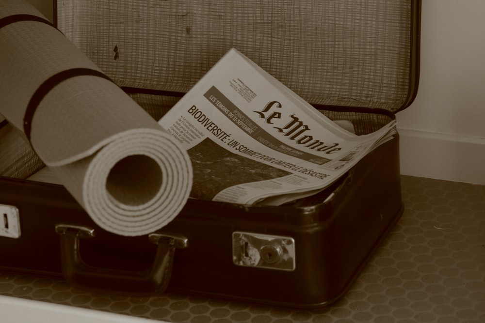 a piece of luggage with a newspaper and a roll of toilet paper