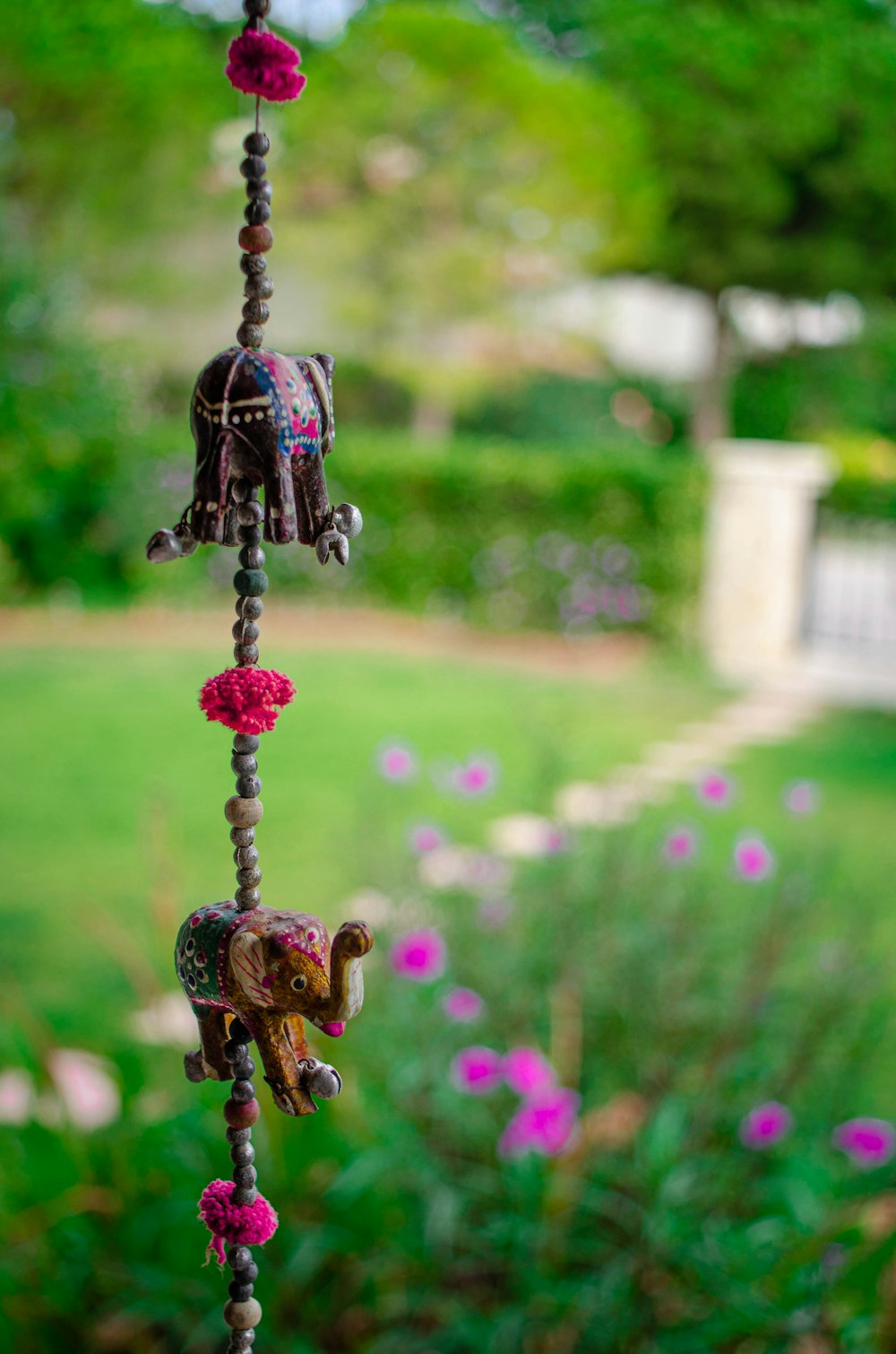 a wind chime in a garden with pink flowers