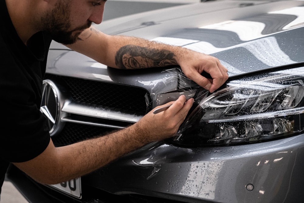 Ein Mann wächst die Motorhaube eines Autos