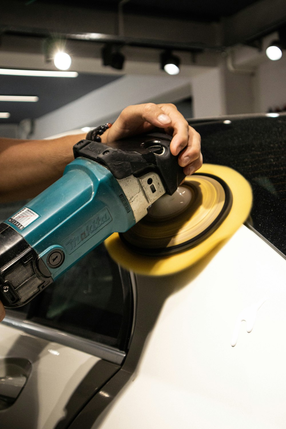 Machine polisher working a coating into a painted panel