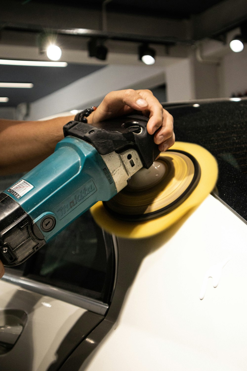 a person sanding a car with a sander