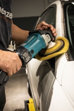 a man sanding a car with a power sander