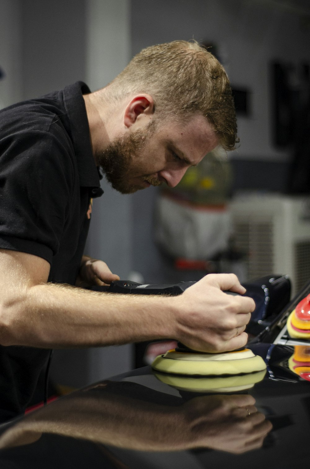 a man in a black shirt polishing a pair of shoes