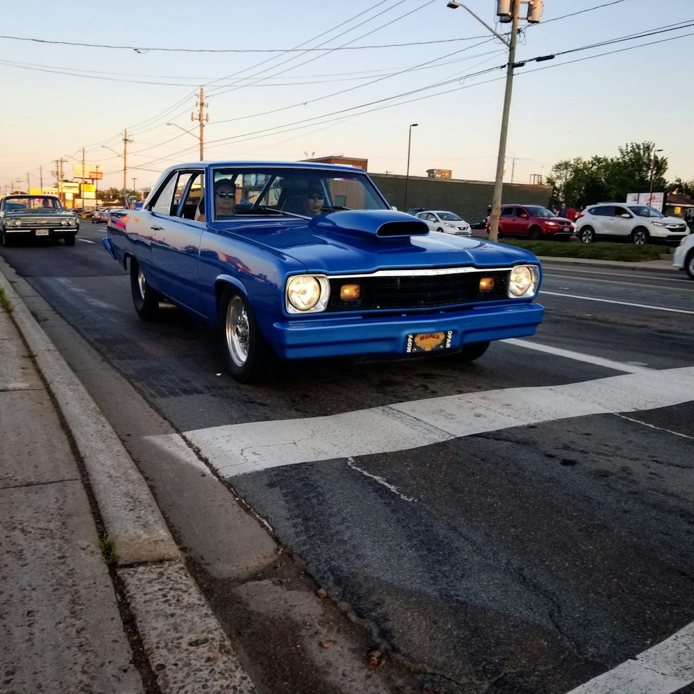a blue car driving down a street next to a traffic light