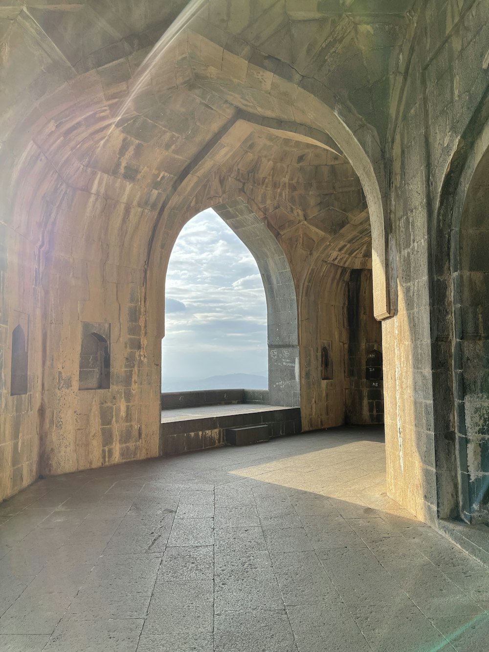 a stone archway with a view of a body of water