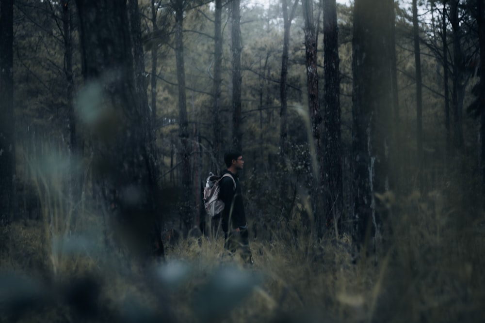 a man walking through a forest with a backpack