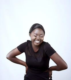 a smiling woman in a black top with her hands on her hips