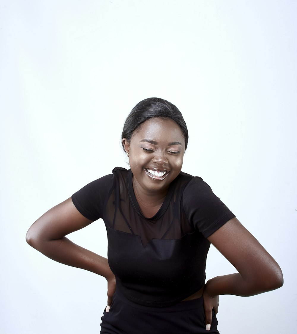 a smiling woman in a black top with her hands on her hips