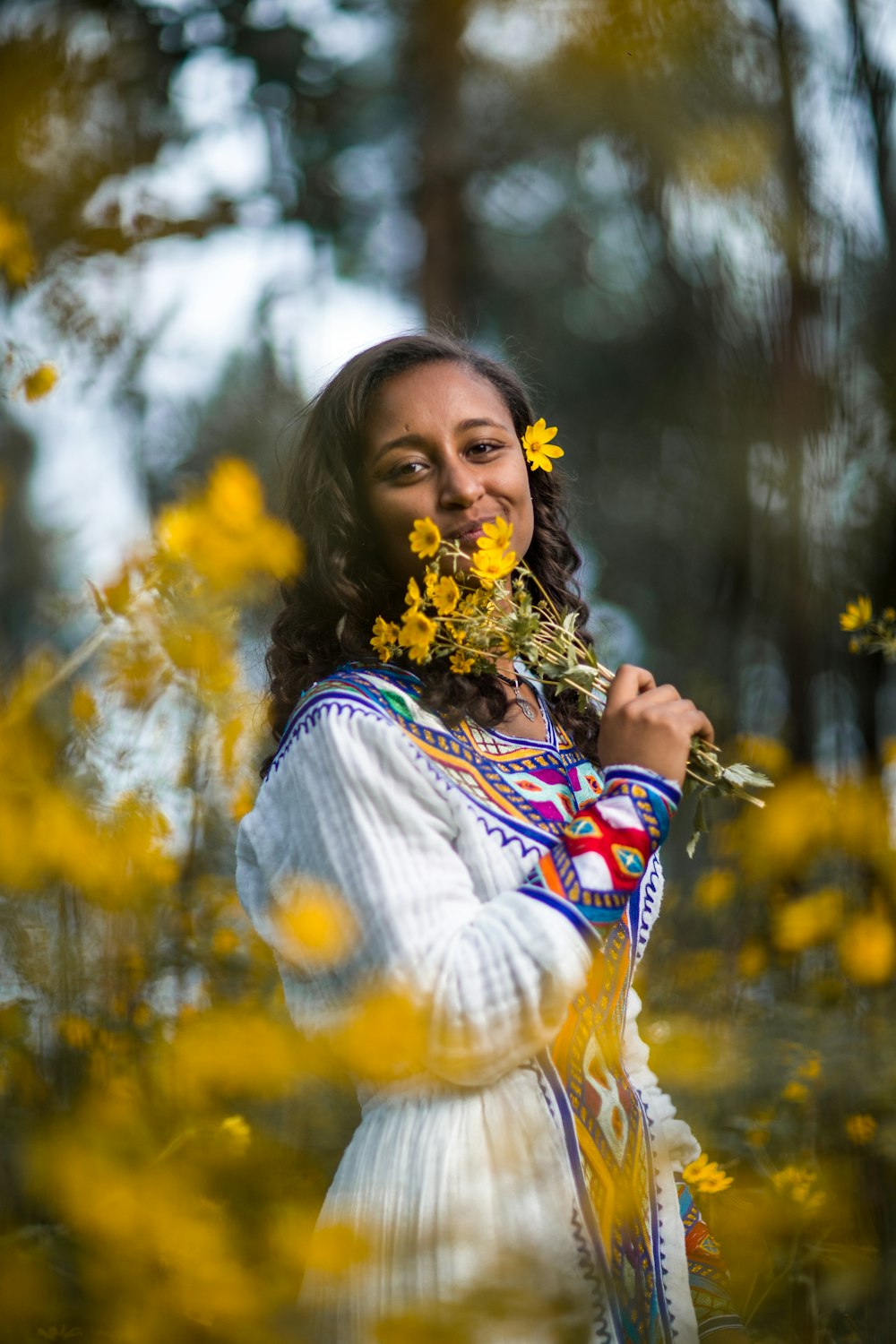 a woman is standing in a field of yellow flowers