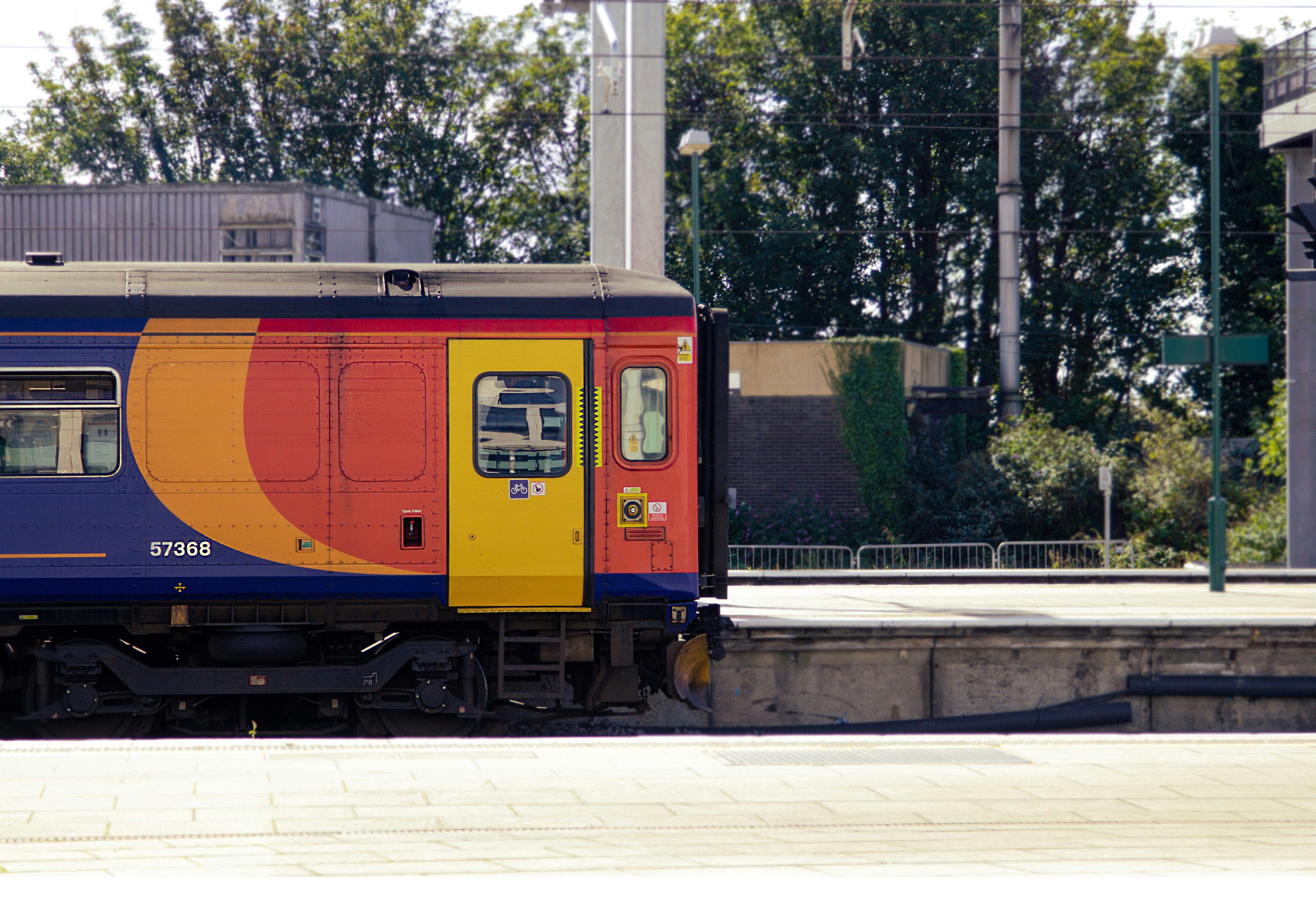 um trem multicolorido está estacionado nos trilhos